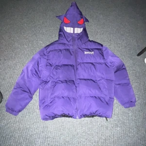 Lila pufferjacka med huva från Kakazzy. Org pris 2500 med frakt: kvitto finns. - Cool lila pufferjacka från Kakazzy med unik huva som har ett ansikte. Jackan har dragkedja och är perfekt för att sticka ut i mängden. Den är långärmad och har en avslappnad passform.