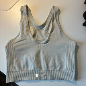 Beige sporttopp från Björn Borg - Säljer en beige sporttopp från Björn Borg i mycket bra skick. Toppen är ribbad och har en tight passform, perfekt för träning. Den är ärmlös med en brottarrygg för extra rörelsefrihet. Superbekväm och stilren design!
