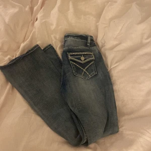 Blå jeans med detaljerade bakfickor - Snygga blå jeans med unika detaljer på bakfickorna. De har en låg midja och en bootcut-stil som ger en avslappnad look. Perfekta för en casual outfit.💕💸