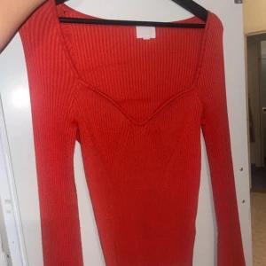 Röd ribbad tröja - Snygg röd ribbad tröja med lång ärm och djup v-ringning. Perfekt för en stilren look.