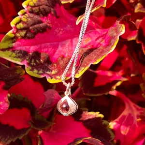 Silverhalsband med röd sten - Säljer ett elegant silverhalsband med en vacker röd sten i hänge. Kedjan är tunn och smidig, perfekt för både vardag och fest. Hänget har en unik design som verkligen fångar ögat. Passar perfekt som en present eller för att skämma bort dig själv!