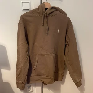 Ralph Lauren Hoodie - Tja,  Säljer nu denna Ralph Lauren hoodien i storlek M i en olivgrön-brun aktig färg. Den är väl omhändetagen och har inga skador eller fläckar. Kontakta gärna för mer frågor!