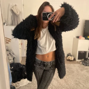 Svart pälsjacka från Nelly - Säljer en snygg svart pälsjacka från Nelly. Jackan har en lång och fluffig design som ger en lyxig känsla. Perfekt för att hålla sig varm och stilren under kyligare dagar. Passar bra till både jeans och klänning. 💕