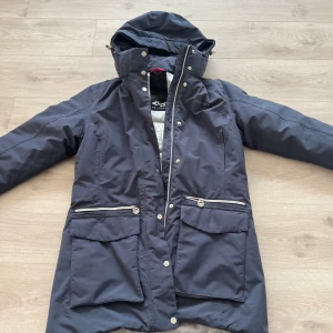 Röhnisch vinterparkas i nyskick! Stl 40 - En snygg och varm vinterjacka med huva i Stl 40. Jackan har flera fickor och en dragkedja framtill. Den är i mycket gott skick och har inte använts mycket (jag har Max använt den 3 gånger). Modell: ”Bootis Parka”. Jag har tyvärr inte pälsen kvar. 