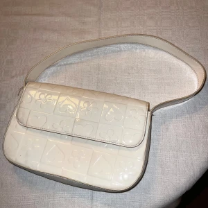 Vit Axelväska, glansig  - Använt få gånger utomlands! Därav lite färgad av att jag haft snäckor i 😅 Men så söt 