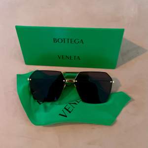 Bottega Veneta-solglasögoni Aviator-modell. Svart glas och guldig metall. Som nya. 