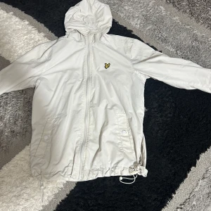 Lyle scott regn jacka - En vit jacka med knapp fickor o band man kan dra ifall man vill göra lite tightare