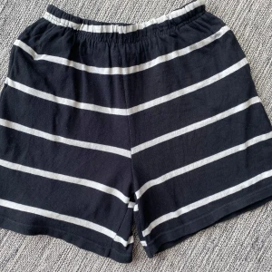 Svarta och vit randiga bomullsskjorta från Foxtrot i strl L. - Använda och förutom att resåren på insidan är lite trasigt är de i fint begagnat skick och inga andra skador som syns utanpå.  Mått Midjan: ca 34 cm Total längd: ca 43 cm Längd från grenen och ner: ca 13 cm  100% bomull  