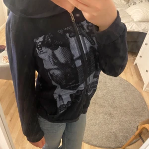 Kofta med tryck - Snygg kofta med luva och ett tryck på magen. Jätte fint skick, sällan använd och bra i storleken! 