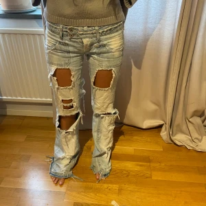 Ljusa slitna jeans - Säljer ett par ljusa jeans som är lågmidjade och flared. Perfekta för en avslappnad och cool stil. Passar bra till vardags eller en chill festkväll. midjemått ca 82 och innerbenslängd ca 85