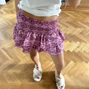 Rosa mönstrad kortkjol - Säljer en superfin rosa kortkjol med ett snyggt mönster. Kjolen har en volangdetalj som ger den en extra touch av stil. Perfekt för sommardagar eller en festlig kväll! 🩷