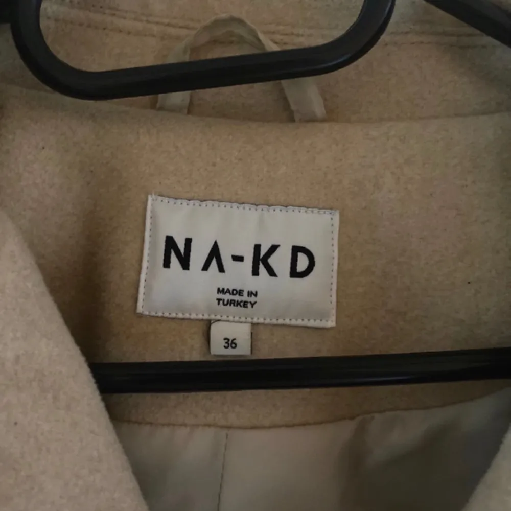 Säljer en superfin beige kappa från NA-KD i storlek 36. Den är perfekt för höst och vår med sin stilrena design och dubbelknäppning. Jackan är croppad och har långa ärmar, vilket ger en modern look. Den är i nyskick och passar perfekt till både vardag och fest!. Takit.
