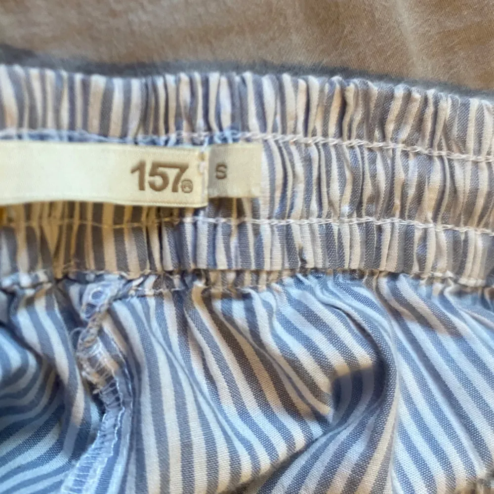 Säljer ett par bekväma randiga pyjamasbyxor från Laget 157 i storlek S. De är blå och vita med en elastisk midja och dragsko för perfekt passform. Lite nötta i grenen! Perfekta för en avslappnad dag hemma. 🩵. Jeans & Byxor.