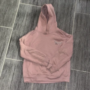 Rosa hoodie från lager 157 - Säljer en supermysig rosa hoodie från lager 157 i storlek 140. Perfekt för kyliga dagar med sin mjuka insida och bekväma passform. Den har en klassisk design med en stor huva och långa ärmar. 
