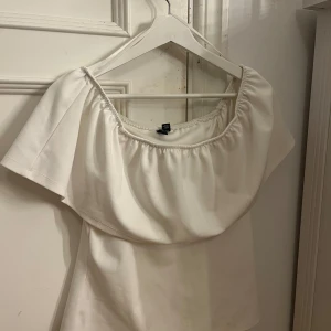 Vit offshoulder topp - Säljer en superfin vit offshoulder topp. Den har en luftig och bekväm passform med korta ärmar. Toppen är i ett mjukt material och passar både till vardags och fest. Perfekt att matcha med jeans eller kjol för en stilren look!