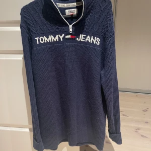 Mörkblå stickad tröja från Tommy Jeans - Säljer en snygg mörkblå stickad tröja från Tommy Jeans. Perfekt för höst och vinter, med långa ärmar och ribbade muddar. Passar både till vardags och lite finare tillfällen. 9/10 för köpt någon månad sen men typ aldrig använd. Inga fel, passar M-L