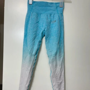 Blå och vita leggings - Säljer ett par snygga blå och vita leggings med ombre-effekt. Perfekta för träning eller en avslappnad dag. De är tighta och bekväma med hög midja för extra stöd. Materialet är stretchigt och andas bra, vilket gör dem idealiska för både yoga och gymmet. Passa på att köpa dessa unika leggings!