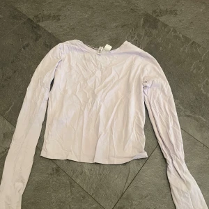 Ljuslila långärmad topp - Säljer en ljuslila långärmad topp i mycket bra skick. Perfekt för vår och sommar, med en enkel och stilren design. Materialet är mjukt och bekvämt, vilket gör den idealisk för vardagsbruk. Passar bra till både jeans och kjol! Den är i storlek S men skulle säga att det är en XS