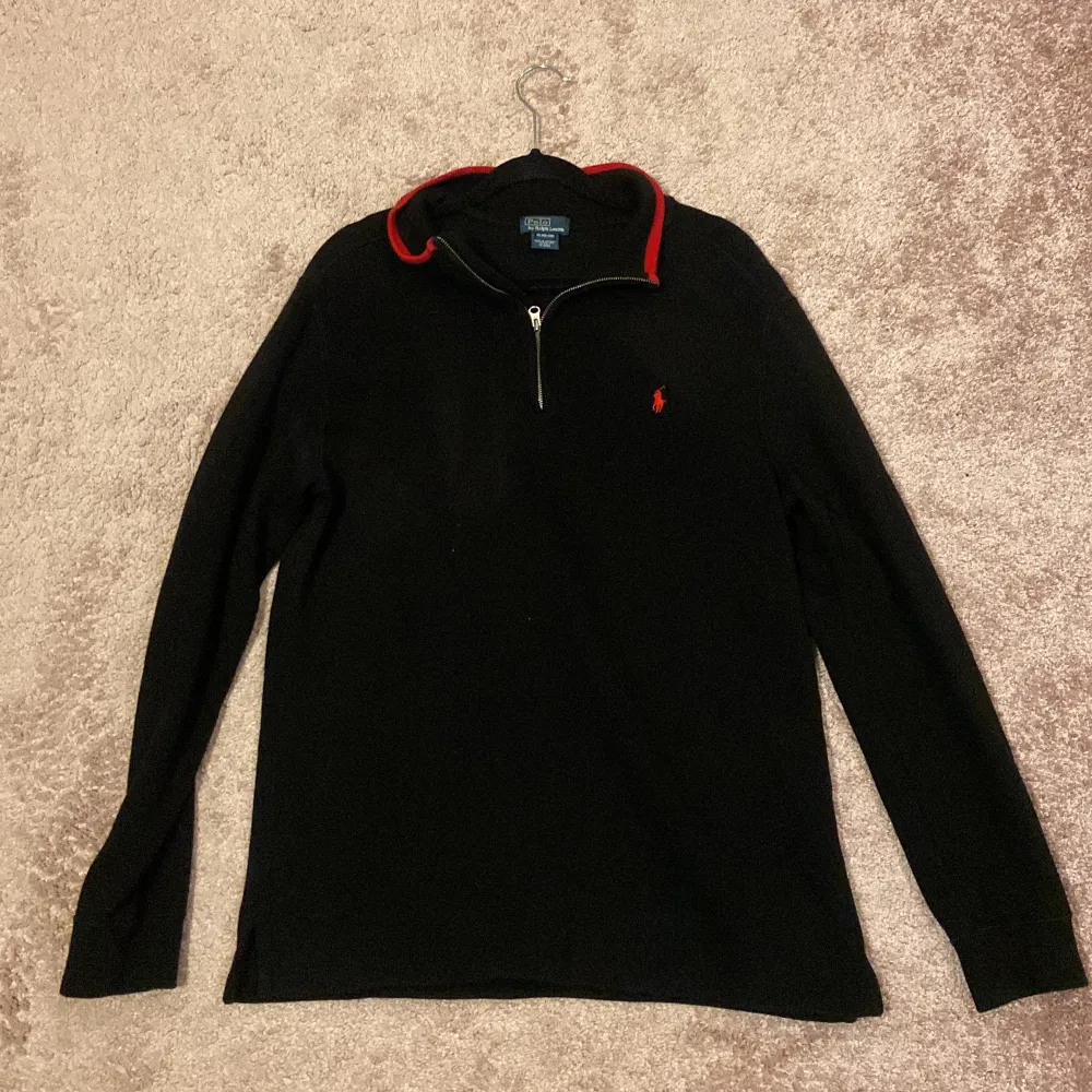 Ralph Lauren Quarter Zip Svart tröja med röd broderad Ralph Lauren logga. Skick: 8/10, Inga skador eller liknande! Storlek: XL 18-20 barn = strl M vuxen. Sitter lite stort på mig som är 173 cm, 60 kg då jag föredrar annan passform. Äkta såklart✅ Mvh!. Tröjor & Koftor.