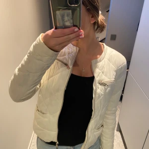 Vit quiltad jacka från Guess - Säljer en snygg vit quiltad jacka från Guess i mycket bra skick. Jackan har dragkedja framtill och två bröstfickor med dragkedjor. Perfekt för höst och vår, med en stilren look som passar till det mesta. Storlek dam M.