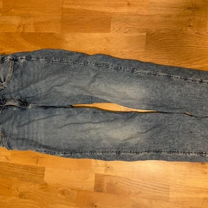 Blå jeans från H&M - Säljer ett par blå jeans från H&M i storlek 164. De har en relaxed fit med justerbar midja och avsmalnande ben. Perfekta för en avslappnad stil och passar till de flesta tillfällen. De är i bra skick och redo för en ny ägare!