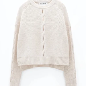 Beige stickad tröja från Filippa K - Superfin beige stickad tröja från Filippa K i mycket bra skick. Den har en snygg flätad detalj framtill och är perfekt för kyliga dagar. Tröjan är croppad och har långa ärmar med ribbade muddar. Perfekt för både höst och vinter!