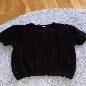 Svart Stickad blus  - En fin svart stickad blus. Det är lite tråd som ticker upp vid högra armen, men inget som syns så tydligt när den sitter på.