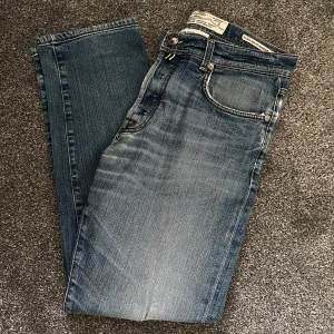 Jacob Cohen jeans - Säljer ett par snygga blå jeans med coola slitningar. De har en klassisk femficksdesign och en knappgylf. Perfekta för en avslappnad stil och passar till det mesta. De är i bra skick och redo för nya äventyr!