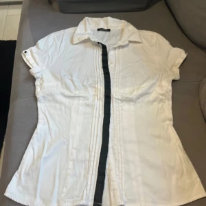Vit kortärmad skjorta från Orsay - Säljer en stilren vit skjorta från Orsay. Den har korta ärmar och knappar framtill. Perfekt för både vardag och festliga tillfällen. Skjortan är i bra skick och passar till många olika outfits. Hör av dig vid intresse! 