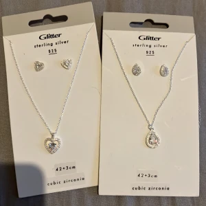 Smyckeset i sterling silver från Glitter - Två eleganta smyckeset i sterling silver 925 från Glitter. Det ena setet har ett hjärtformat hänge och matchande örhängen, medan det andra har ett droppformat hänge med matchande örhängen. Båda seten är dekorerade med cubic zirconia för extra glans. 300 kr st eller båda 500kr😁 perfekt som present/julklapp❤️