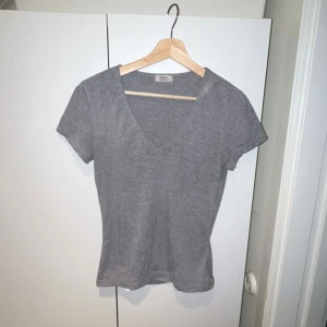 Grå t-shirt från Only - Säljer en enkel och stilren grå t-shirt från Only. Den har en v-ringad hals och korta ärmar, perfekt för vardagsbruk. Passar bra till jeans eller kjol. Knappt andvänd och inga defekter🫶🏼