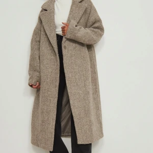 Beige kappa - Snygg och stilren beige kappa med lång passform och klassisk krage. Perfekt för kyligare dagar med sin mjuka och bekväma design. Den här kappan är något oversized och gjord av ull och har en krage med slag, en knappstängning på framsidan, långa ärmar, snedställda sidofickor. Aldrig använd, blivit lite skrynklig för den legat i en låda. Bilder finns :) 