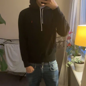Svart ralph lauren hoodie - Säljer en stilren ralph lauren hoodie, Skicket är mycket bra då det inte finns några defekter eller liknande. 
