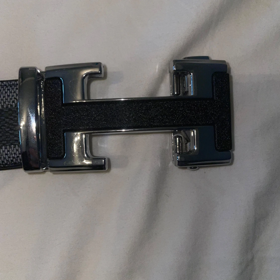 Svart och grått rutigt bälte med metallspänne