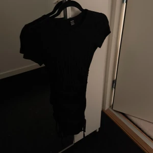 Svart kortklänning - Snygg svart kortklänning med korta ärmar och åtsittande passform. Perfekt för en kväll ute eller en speciell tillställning.