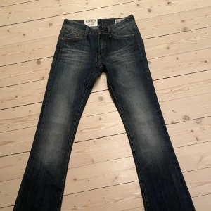 Mörkblå bootcut jeans från Crocker - Säljer ett par mörkblå bootcut jeans från Crocker i modellen Pep! De är lågmidjade och liknar dem trendiga Weekday jeansen med dem vita skuggorna längs låren. Storleken är 25 i midja och 34 i längd. Helt oanvända med lapp kvar. Original pris 600
