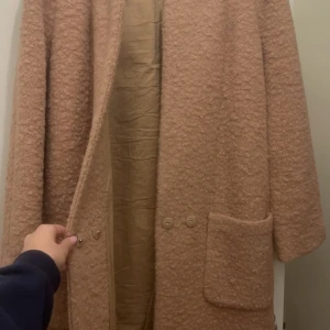 Beige kappa från Ganni - Säljer en stilren beige kappa från Ganni. Den har en rak passform med stora fickor framtill och knappar för stängning. Perfekt för höst och vår, med en mjuk och bekväm känsla. Pris kan diskuteras 