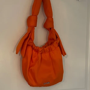 Orange väska från Ganni och andra väskor - Snygg orange väska från Ganni med knutna detaljer på axelremmen. Perfekt för att ge en färgklick till din outfit. 2 vita väskor, en denim väska och en moccabrun väska i läder. Vita väskorna 100 styck, ganni väslan 800kr och denim/mocca 100kr