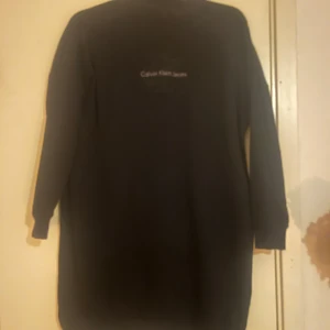 Svart långärmad tröja från Calvin Klein Jeans - Säljer en stilren svart långärmad tröja från Calvin Klein Jeans. Perfekt för en avslappnad look med sin enkla design och bekväma passform.