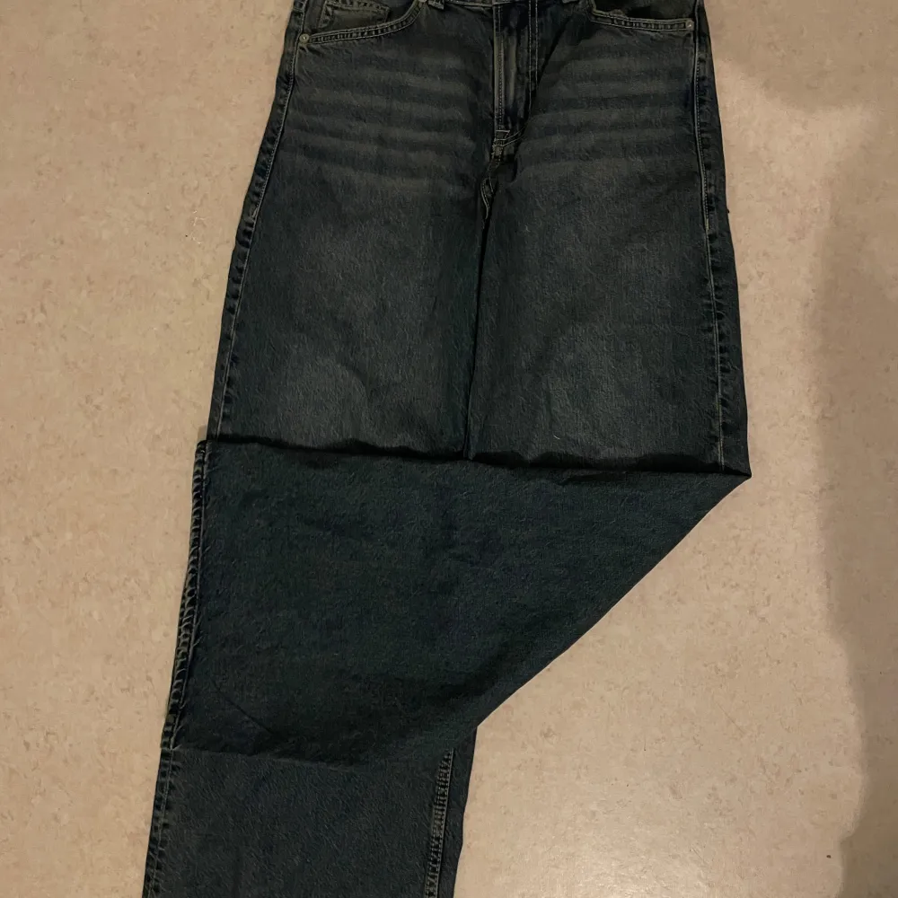Säljer ett par blåa jeans från H&M i storlek 34. De har en klassisk femficksdesign och en rak passform. Perfekta för en avslappnad stil. Byxorna är helt nya men var för korta så att byxorna är uppsprättade längst ner. . Farkut & Housut.