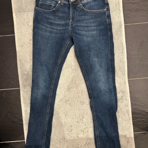 Blå jeans från Dondup - Snygga blå jeans från Dondup med klassisk femficksdesign och knappgylf. Perfekta för en avslappnad stil med en modern touch. De har en normal passform och är tillverkade i slitstarkt denim. W29 modell george nyskick