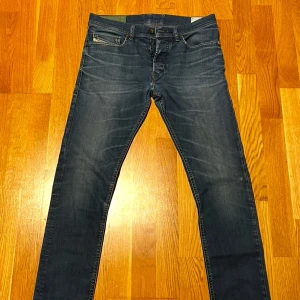 Mörkblå jeans från Diesel - Snygga mörkblå jeans från Diesel med klassisk femficksdesign och knappgylf. Jeansen har en straight passform och är perfekta för en avslappnad stil. Diesel-logotypen syns på den lilla fickan framtill.