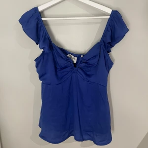 Blå topp från Aware - Snygg blå topp från Aware med korta ärmar och rynkdetaljer fram och bak. Använd en gång