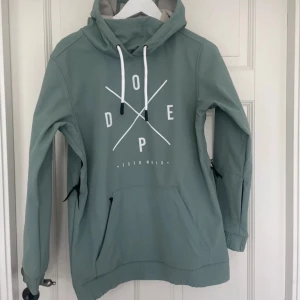 Grön hoodie från Dope - Snygg grön hoodiejacka från Dope med tryck framtill. Den har en stor luva med vita dragsnören och en praktisk magficka. Perfekt för en dag i skidbacken antingen på brädan eller på skidorna😁Jackan är aldrig använd och har därför ett nyskick. Vid frågor tveka inte på att höra av dig!!
