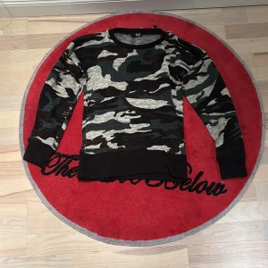 Camouflage tröja från Glad News - Säljer en cool camouflage tröja från Glad News. Tröjan har långa ärmar och en klassisk rund halsringning. 