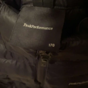 Svart dunjacka från Peak Performance - Säljer en svart dunjacka från Peak Performance. Jackan har en dragkedja framtill och är långärmad. Perfekt för kyligare väder med sin pufferdesign som håller värmen.