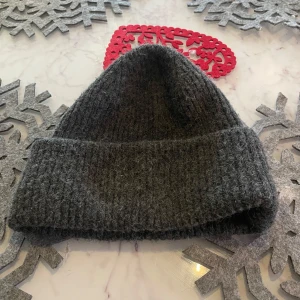 Grå ribbad mössa från 157 - Snygg och varm grå mössa från 157 med ribbad design. Perfekt för kyliga dagar och enkel att matcha med olika outfits.