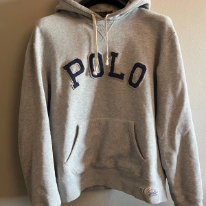 Grå hoodie från Ralph Lauren - Säljer en klassisk grå hoodie från Ralph Lauren med stor POLO-text i blått på framsidan. Tröjan har en bekväm passform och är i storlek L men passar även M! Tröjan har inte defekter och har knappt används då den var för liten för mig. Hör av dig vid frågor! Pris kan såklart diskuteras vid snabb affär.
