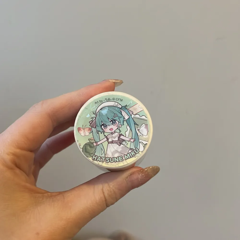 Säljer en rulle dekorativ tejp med ett färgglatt anime-motiv. Tejpen har en vit bas med illustrationer av en karaktär med långt blått hår och olika små detaljer som ger en lekfull känsla. Perfekt för att dekorera anteckningsböcker eller paket.. Asusteet.
