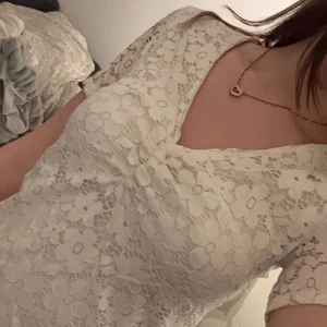 Vit spetsblus med v-ringning - Säljer en elegant vit spetsblus med v-ringning och korta ärmar. Perfekt för en stilren look med vackert blommönster i spetsen. Storlek m men sitter som en s